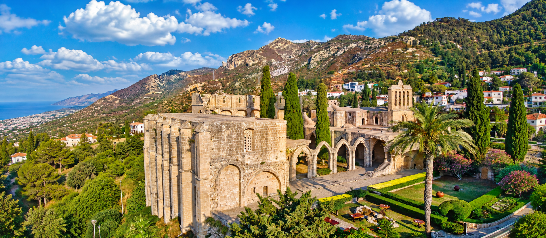 Girne yakınlarındaki Bellapais Manastırı'nın Gotik kemerlerini, taş avlusunu ve çevresindeki manzarayı betimleyen görsel