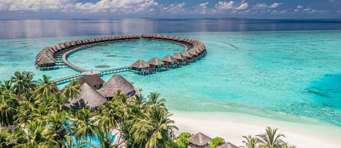 Maldivler’de turkuaz deniz üzerinde su üstü bungalovlar ve beyaz kum plajları